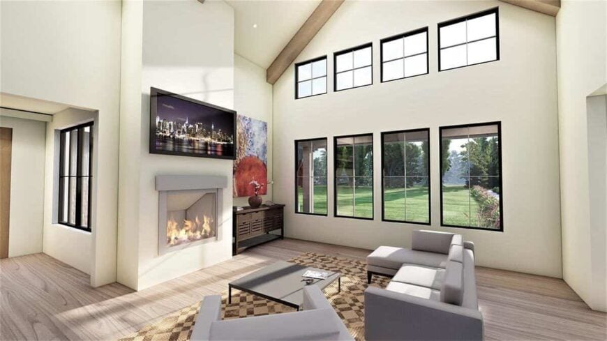 The great room has gray seats, a wall of windows, and a TV mounted above the fireplace.