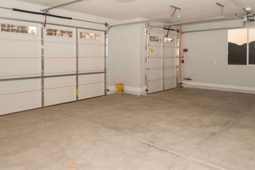 The garage has concrete flooring, paneled doors, and windows allowing natural light in.