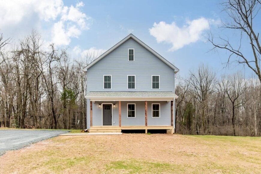 Front exterior view with a gable roof and a covered entry porch lined with rustic timbers.