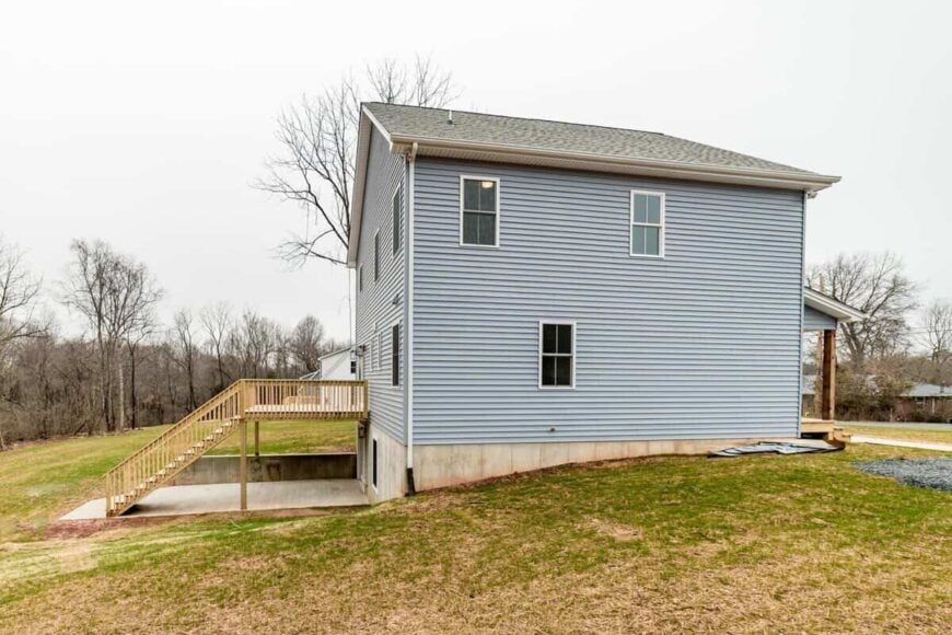 Side exterior view with blue horizontal siding and white framed windows.