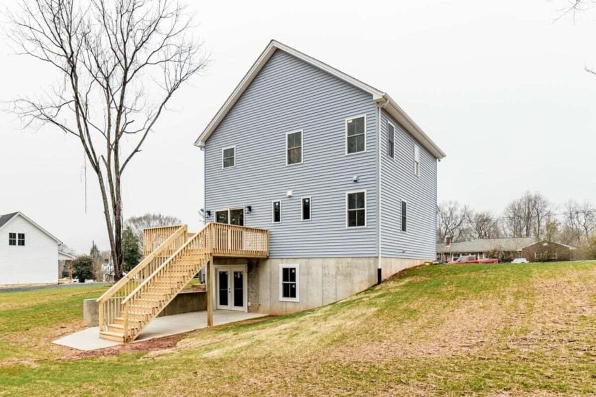 Rear exterior view showcasing the walkout basement and a sun deck with a wooden staircase.