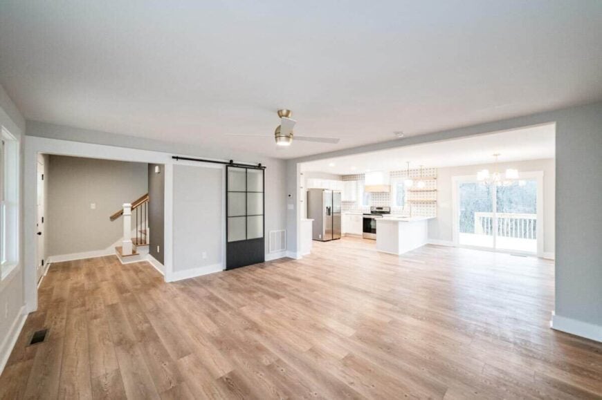 An open living space with light gray walls and hardwood flooring. A sliding barn door conceals the laundry room.