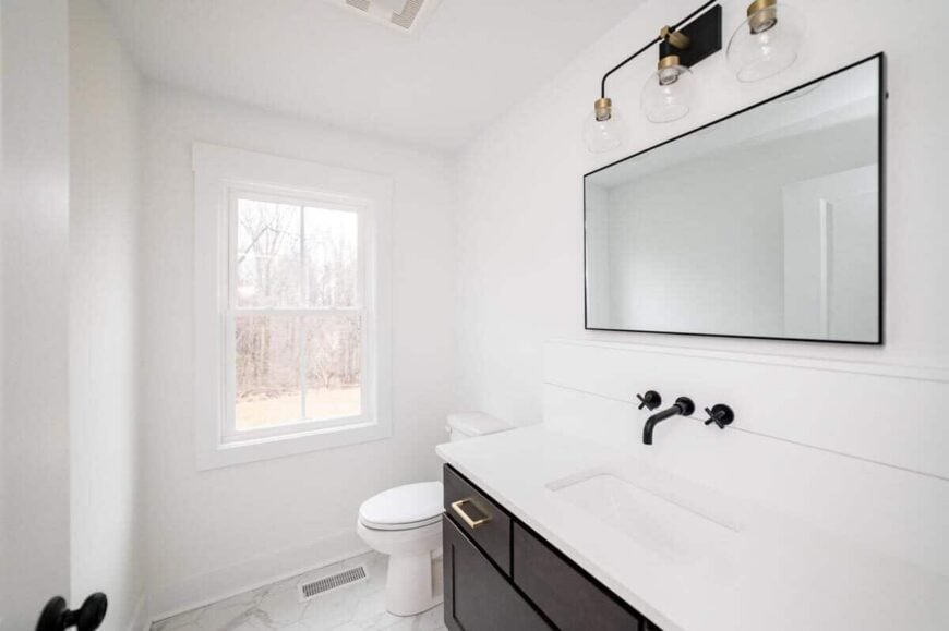 The white walls in this bathroom are contrasted by the dark wood cabinets of the vanity.