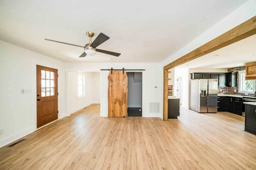 Living room with hardwood flooring and a ceiling fan. A sliding barn door reveals the laundry room.
