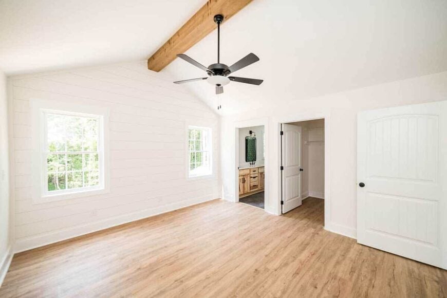 Primary bedroom with a walk-in closet, a private bath, and a cathedral ceiling lined with an exposed wood beam.