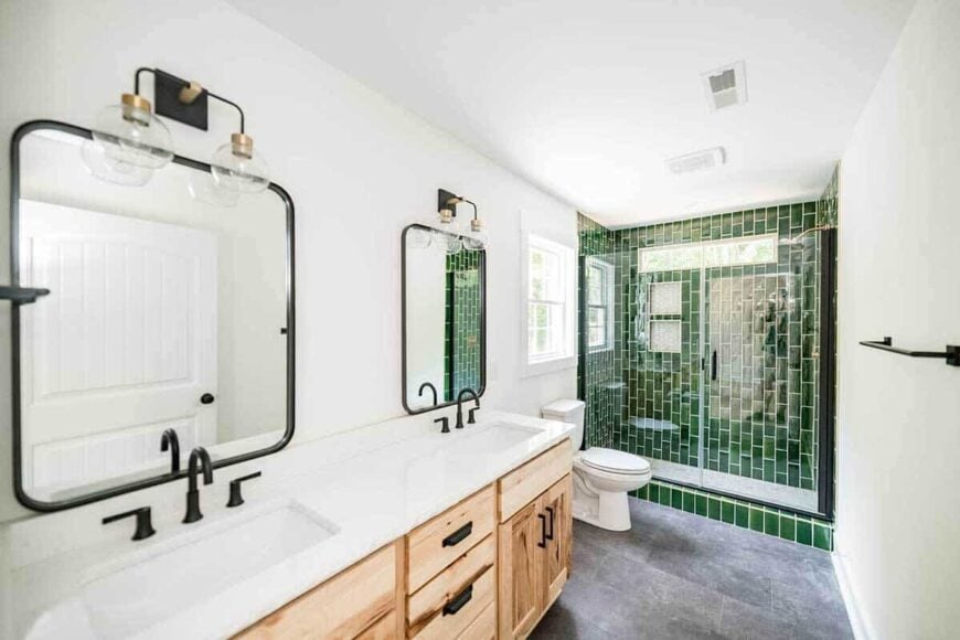 The primary bathroom offers a dual sink vanity, s toilet, and a walk-in shower highlighted by emerald green tiles.