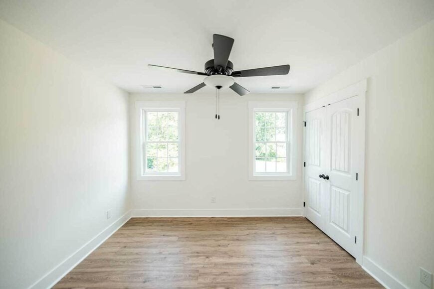 This bedroom has hardwood flooring and a walk-in shower enclosed in white double doors.