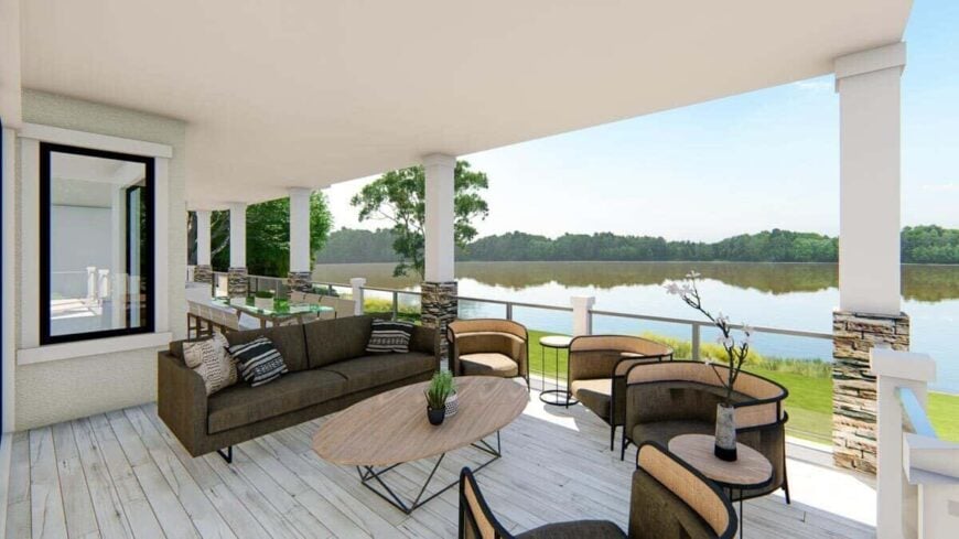Covered porch with a dark sofa, round back chairs, and an oval coffee table over wide plank flooring.