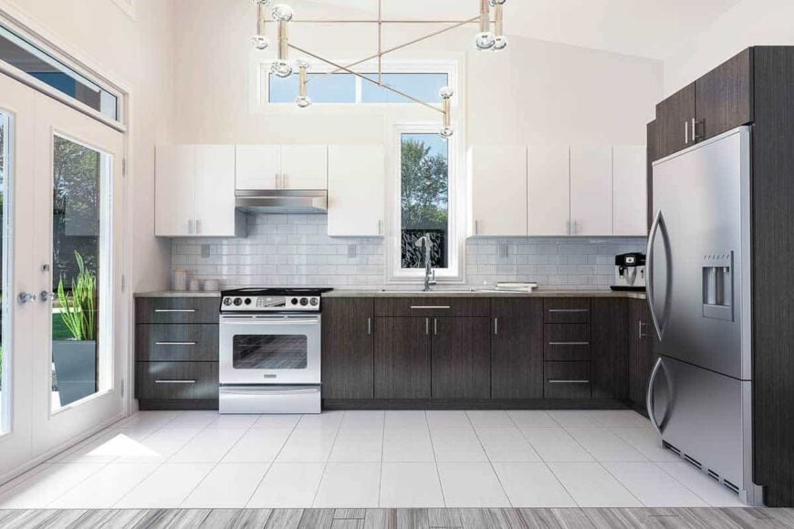 The kitchen has contrasting cabinets, a contemporary chandelier, and stainless steel appliances.