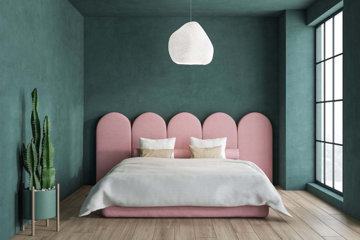 A room with indoor cactus plant and pink headboard.