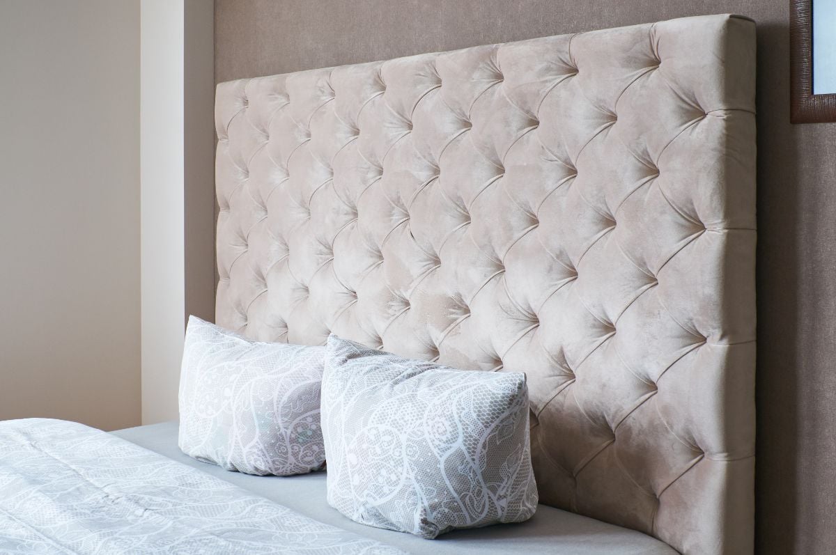 A room with a large headboard and pillows.