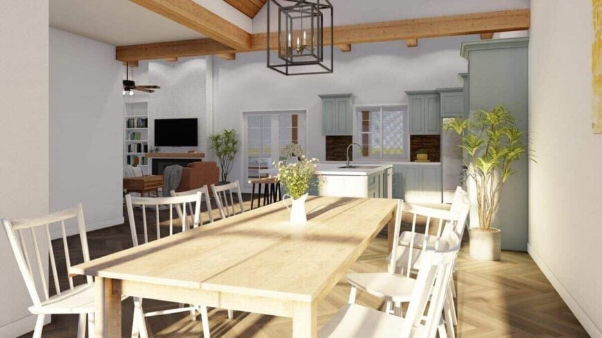 An open layout view of the dining area, kitchen, and living room crowned with vaulted and beamed ceilings.