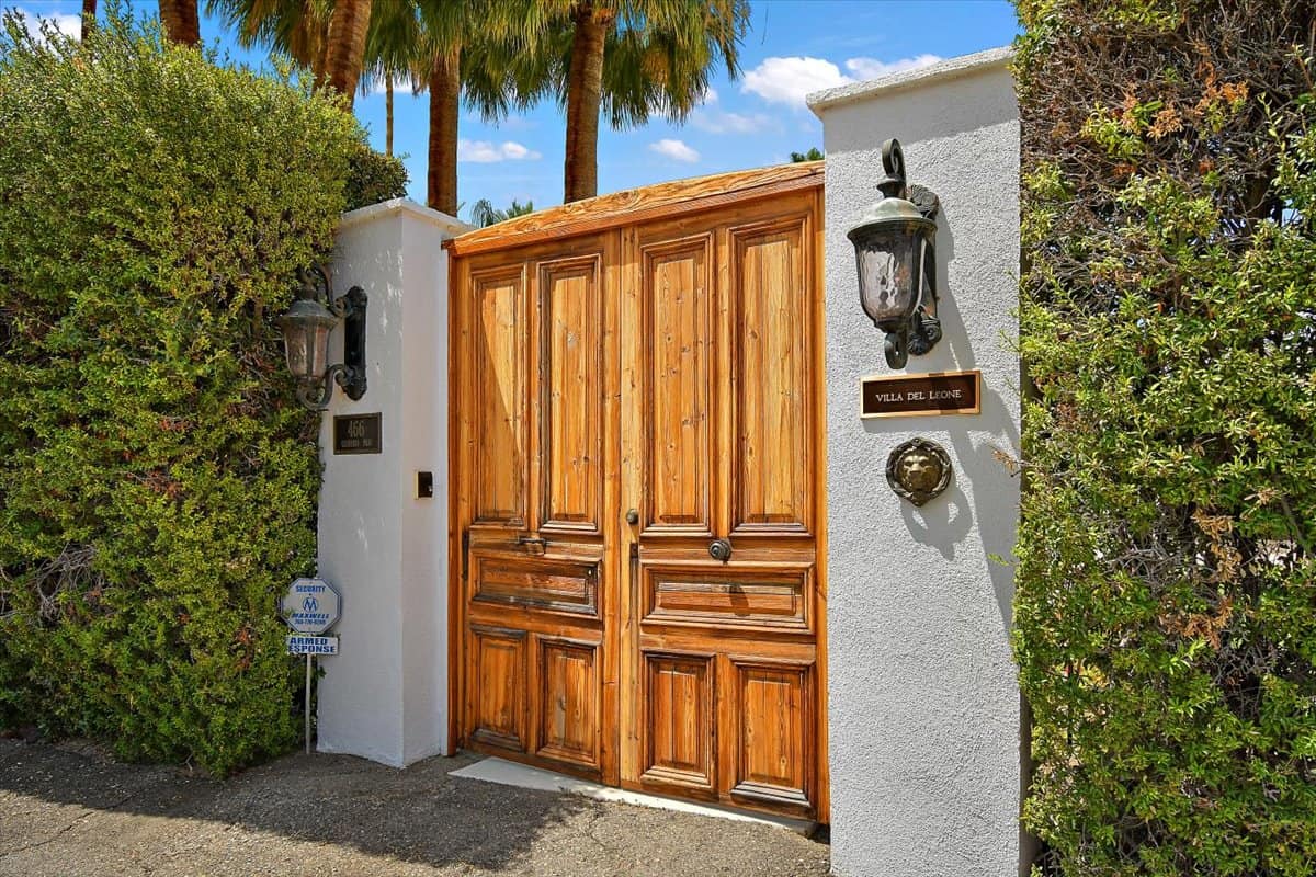 Main entrance with carved double-entry doors and privacy hedges. Image courtesy of Toptenrealestatedeals.com.