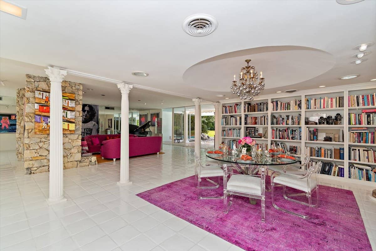 The dining room features a round glass dining set and a vintage chandelier that hangs from the concave ceiling. Image courtesy of Toptenrealestatedeals.com.