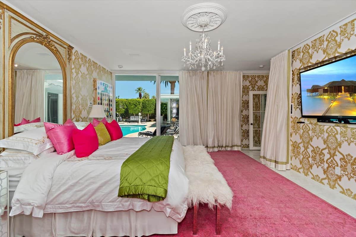 The primary bedroom is loaded with luxury amenities including a large TV and direct access to the pool. Image courtesy of Toptenrealestatedeals.com.