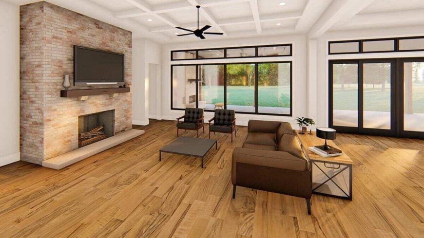 The living room has a coffered ceiling, dark seats, and a brick fireplace with a TV on top.