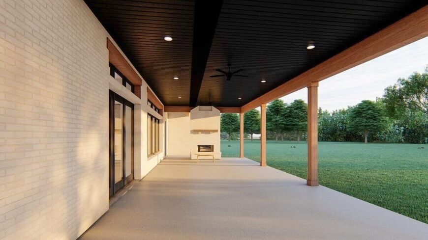 Covered porch with concrete flooring, wood-paneled ceiling, an outdoor fireplace, and rustic columns.