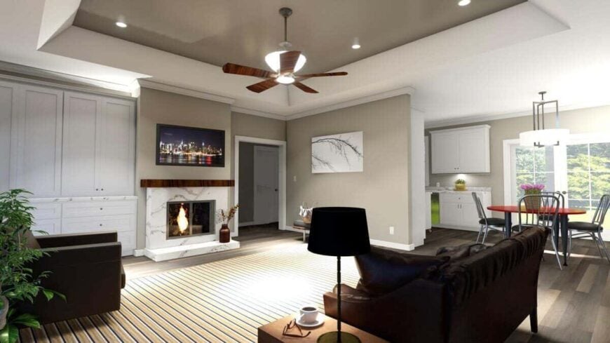 Living room with a tray ceiling, brown seats, full-height cabinets, and a marble fireplace topped with a TV.