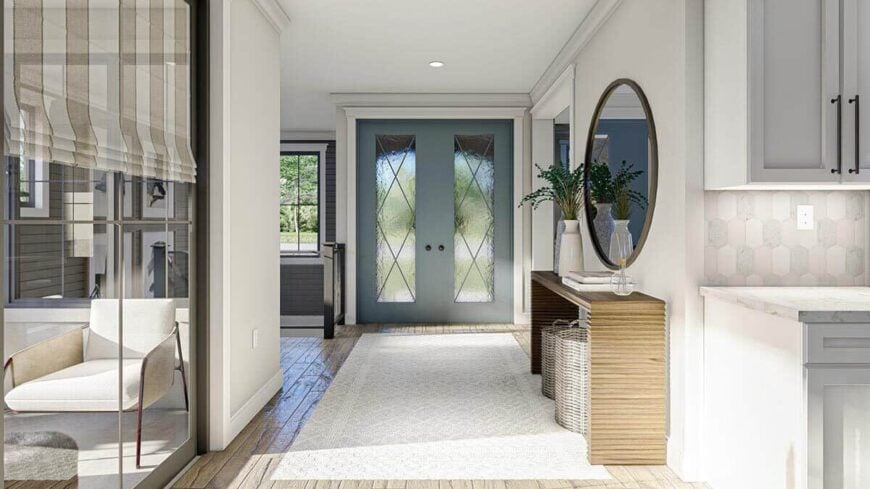 The entry includes a wooden console table topped by vases and a huge round mirror.