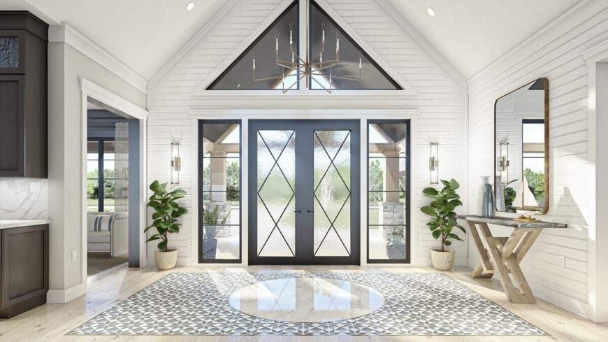 Foyer with a cathedral ceiling, a rustic console table, and a french entry door surrounded by transoms and side lights.