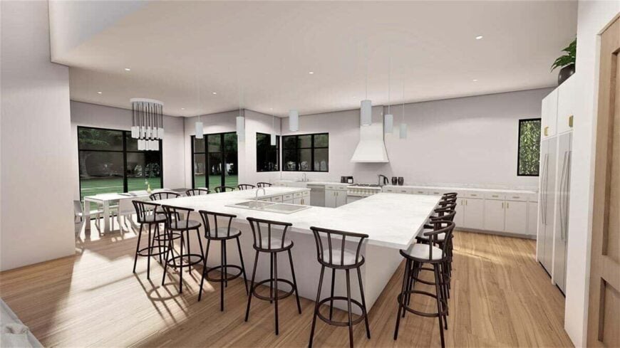 Eat-in kitchen with marble countertops, a wooden dining set, and an immense island fitted with double sinks.