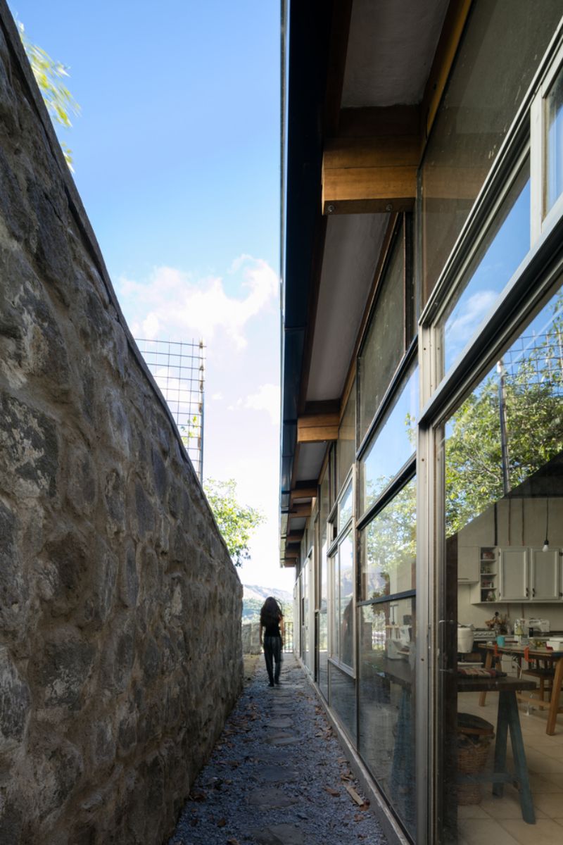 A woman walking along the outside corridor of the house.