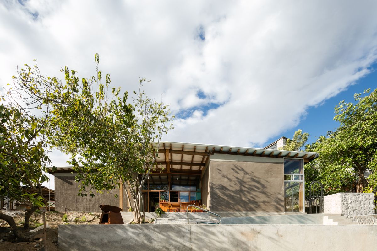 The exterior finish of the house made of the mud walls, concrete beams and flanked by the recycled windows.