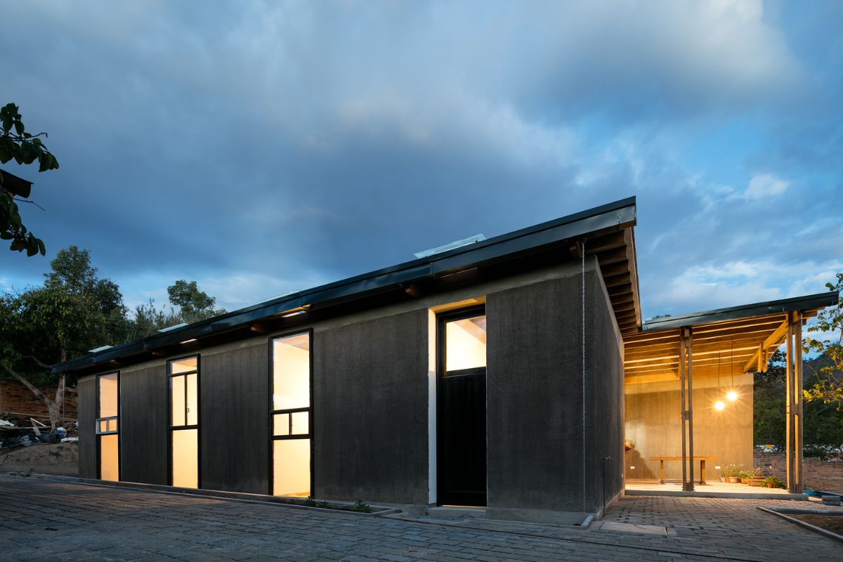 The exterior finish of the house made of the mud walls, concrete beams and flanked by the recycled windows.