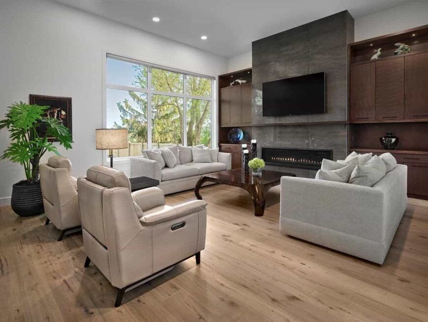 Living room with modern seats, a wooden coffee table, and an electric fireplace topped with a TV.