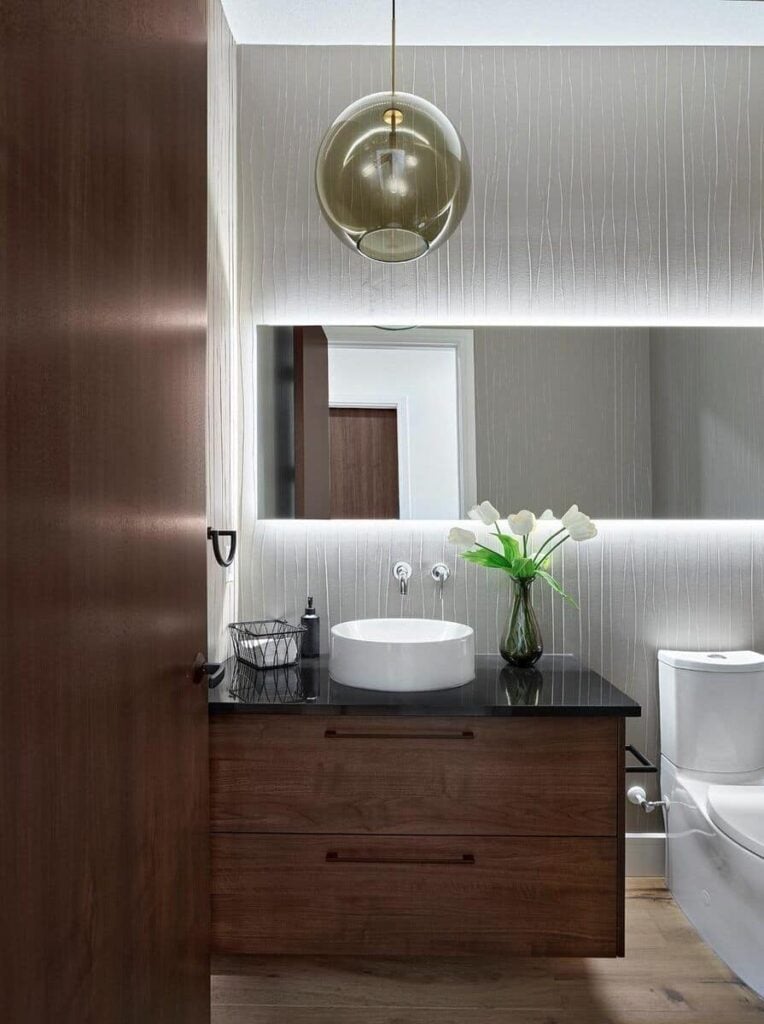A glass-globe pendant and led lighting in the mirror illuminate the powder room.