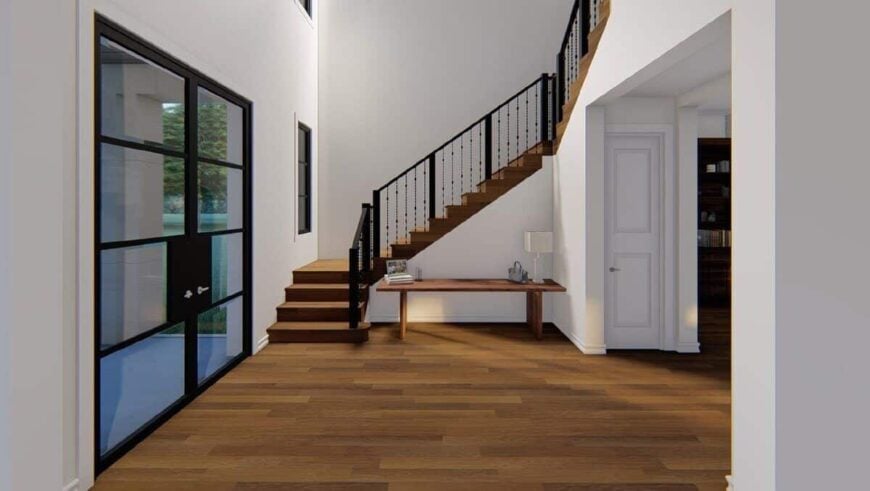 A large french door opens into the soaring foyer with a wooden staircase complemented by a matching console table.