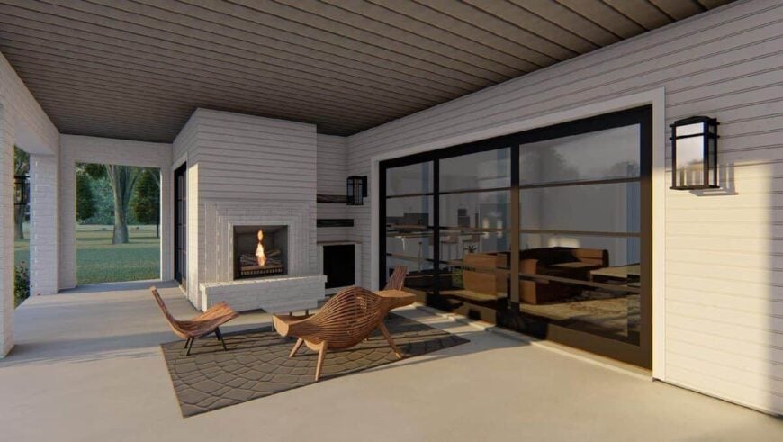 The outdoor living is filled with a fireplace and contemporary chairs that sit on a gray area rug.
