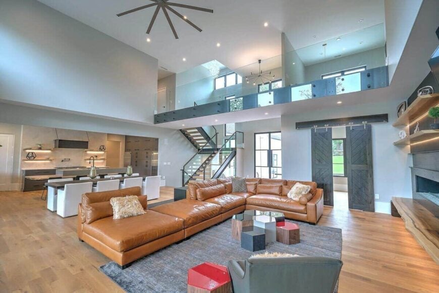 The living room features a tall ceiling and a leather L-shaped sectional paired with a modular coffee table.