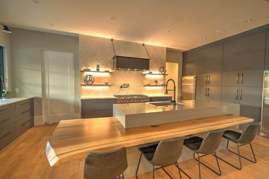 The kitchen offers custom cabinetry, stainless steel appliances, and a center island integrated with a wooden eating bar.