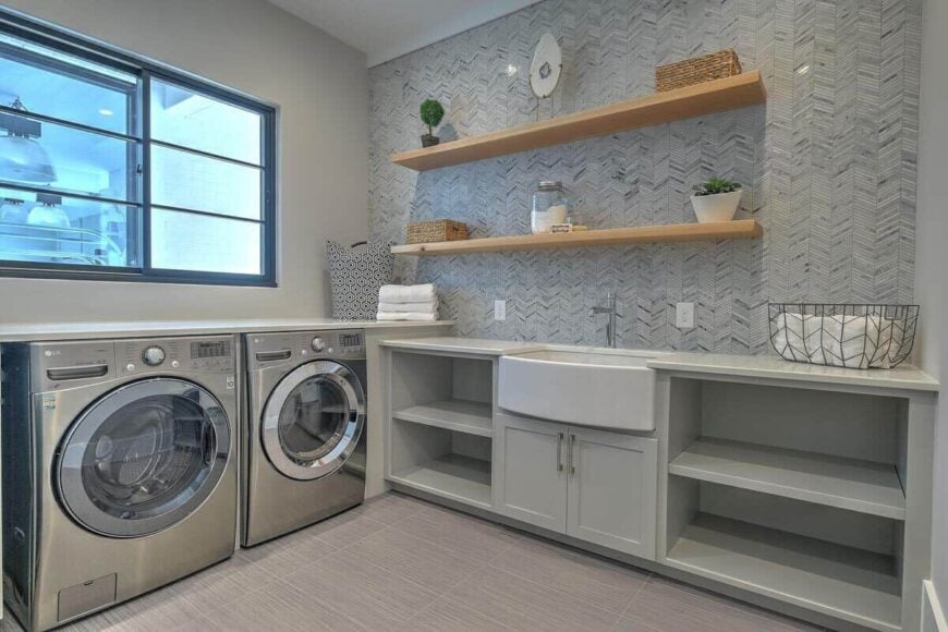 Laundry room with built-in shelves, washer and dryer, multiple counters, and a utility sink topped with wooden floating shelves.