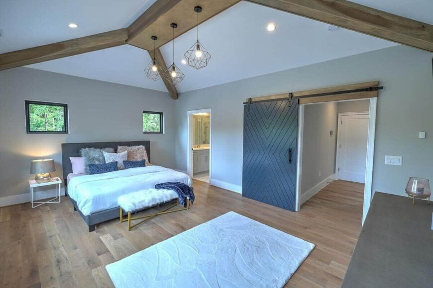 This bedroom has a hardwood floor, a private bath, and a large barn door that reveals the walk-in closet.