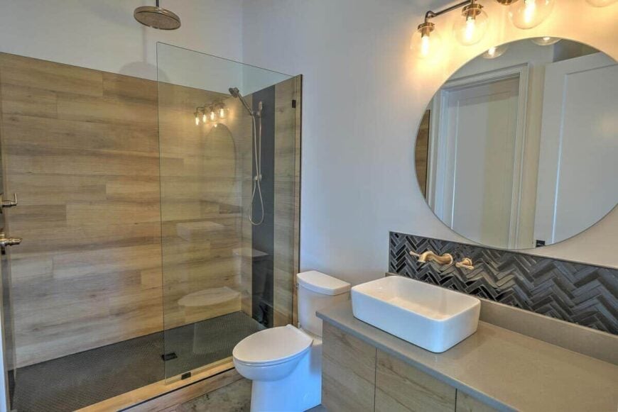 This bathroom offers a walk-in shower and a vessel sink vanity brightened by warm sconces.