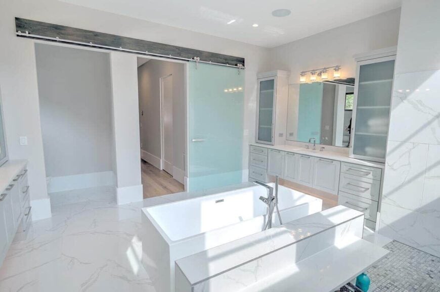 Primary bathroom with separate his and her sink vanities, and a freestanding tub situated in the middle.