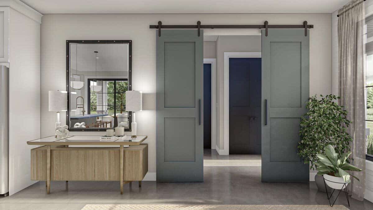 Double sliding barn doors reveal the formal entry. On its side is a wooden console table topped with a framed mirror.