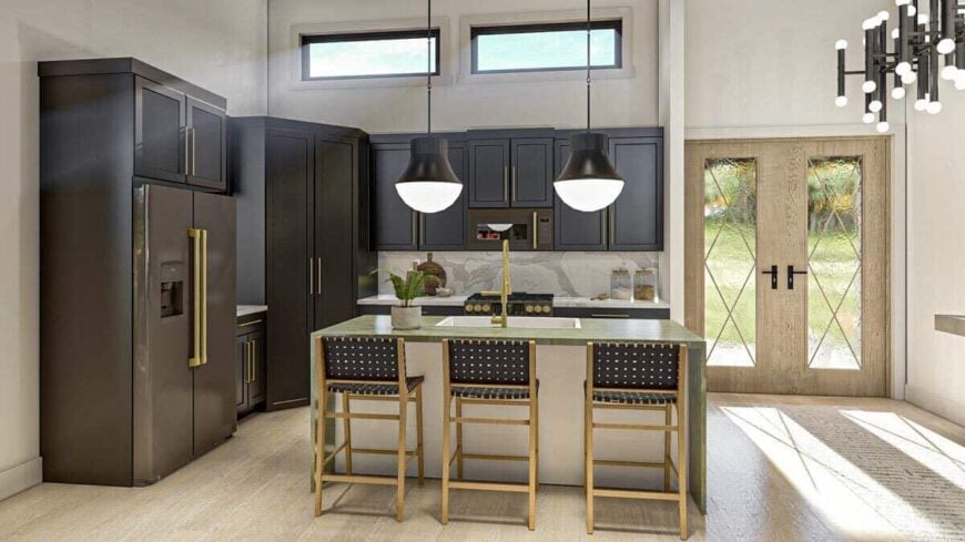 The kitchen has a breakfast island, slate appliances, and dark cabinets accentuated with brass handles.