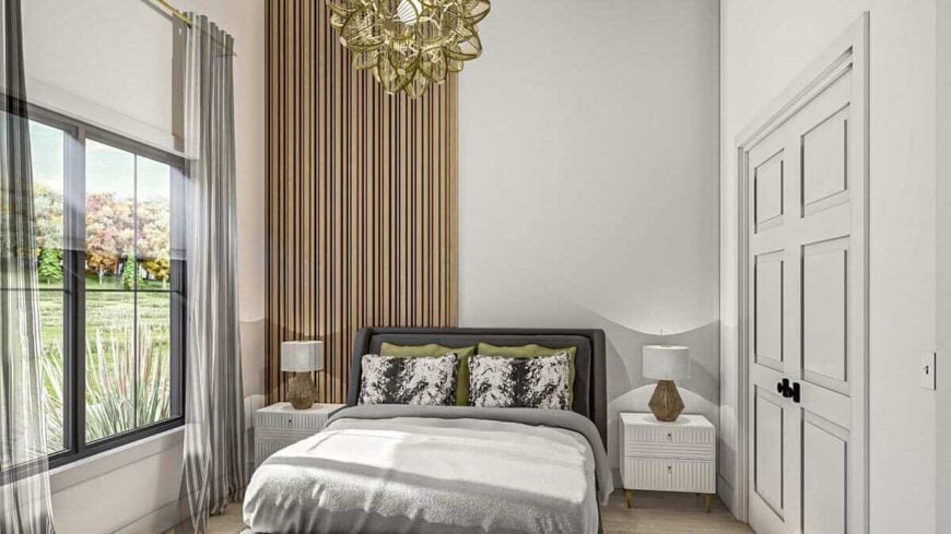 This bedroom has a comfy upholstered bed, an ornate brass chandelier, and large windows allowing natural light in.