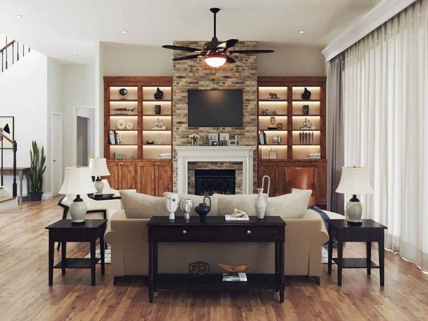 The living room features beige seats and a brick fireplace with a TV on top flanked by wooden built-ins.