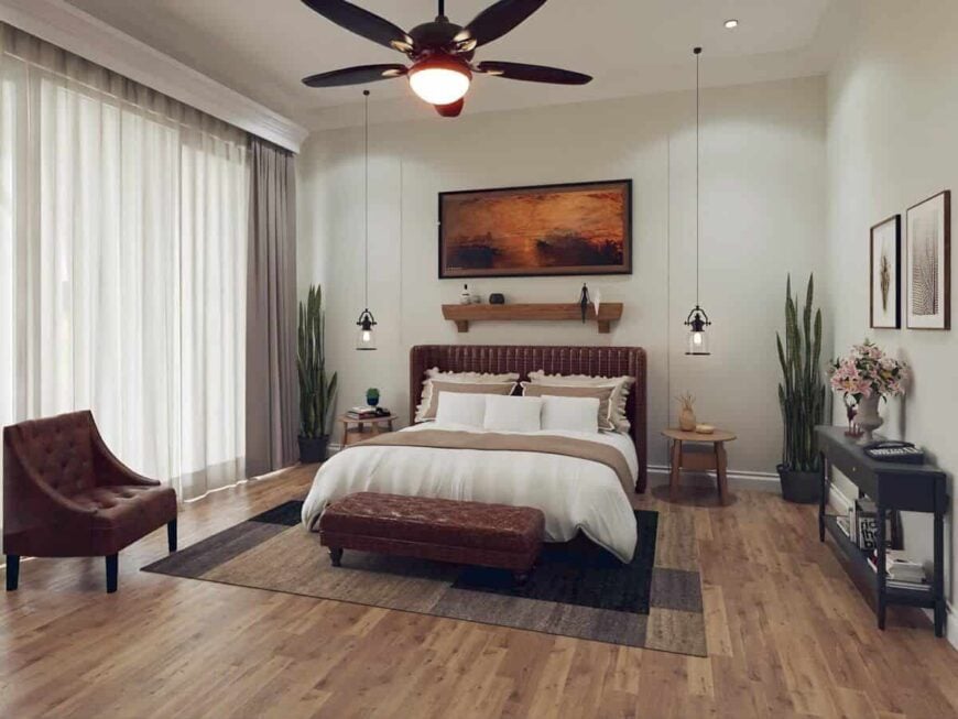 Primary bedroom with leather upholstered bed and seats, hardwood floor, and floor-to-ceiling windows dressed in neutral drapes.