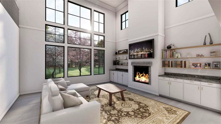 The living room has an L-shaped sofa, an electric fireplace with a TV on top, and huge windows that provide magnificent views of the expansive yard.