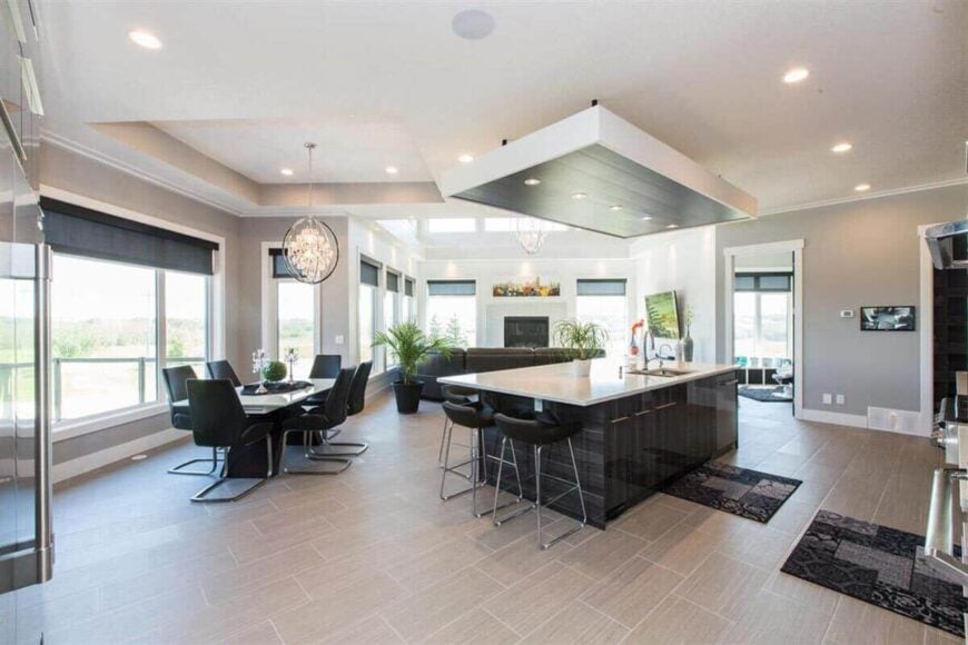 An open layout view of the kitchen, breakfast nook, and living room with vinyl flooring and surrounding windows.