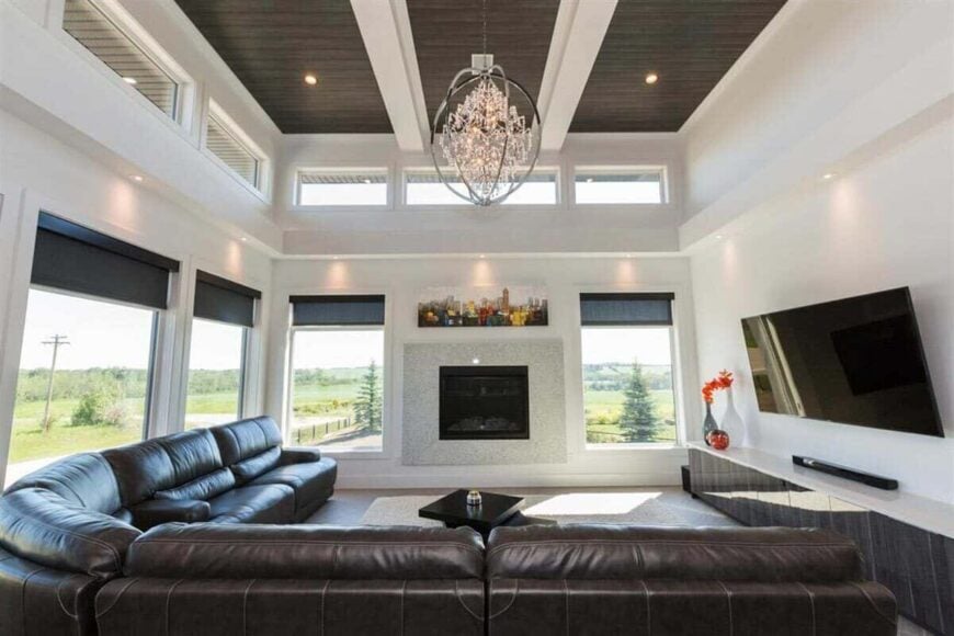 The living room features an electric fireplace, a wall-mounted TV, and a tall ceiling lined with exposed beams.