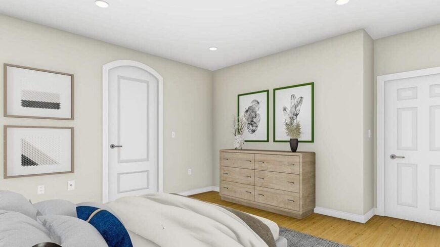Primary bedroom with a comfy bed, a wooden dresser, and framed artworks gracing the white walls.