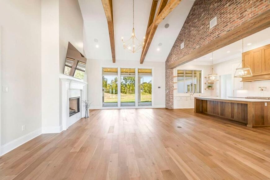 Living room with hardwood floor and a cathedral ceiling framed with exposed trusses.
