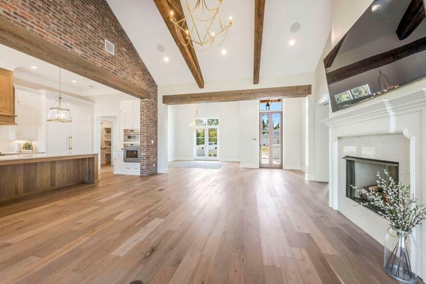 The vaulted living room, kitchen, and dining area flow seamlessly with each other and are defined by wood beams.