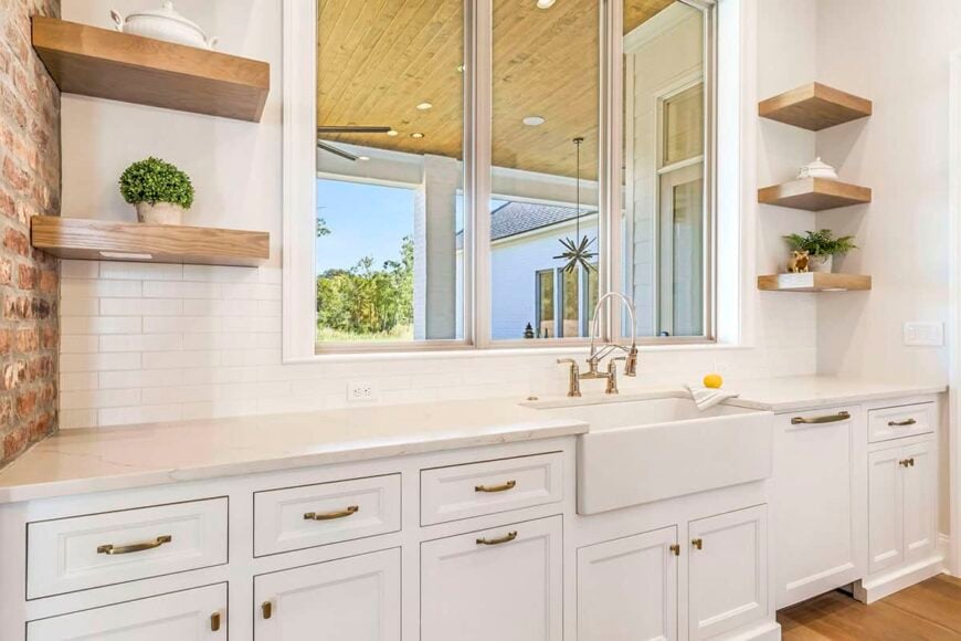 The kitchen includes a farmhouse sink and a view of the covered porch and the backyard beyond.